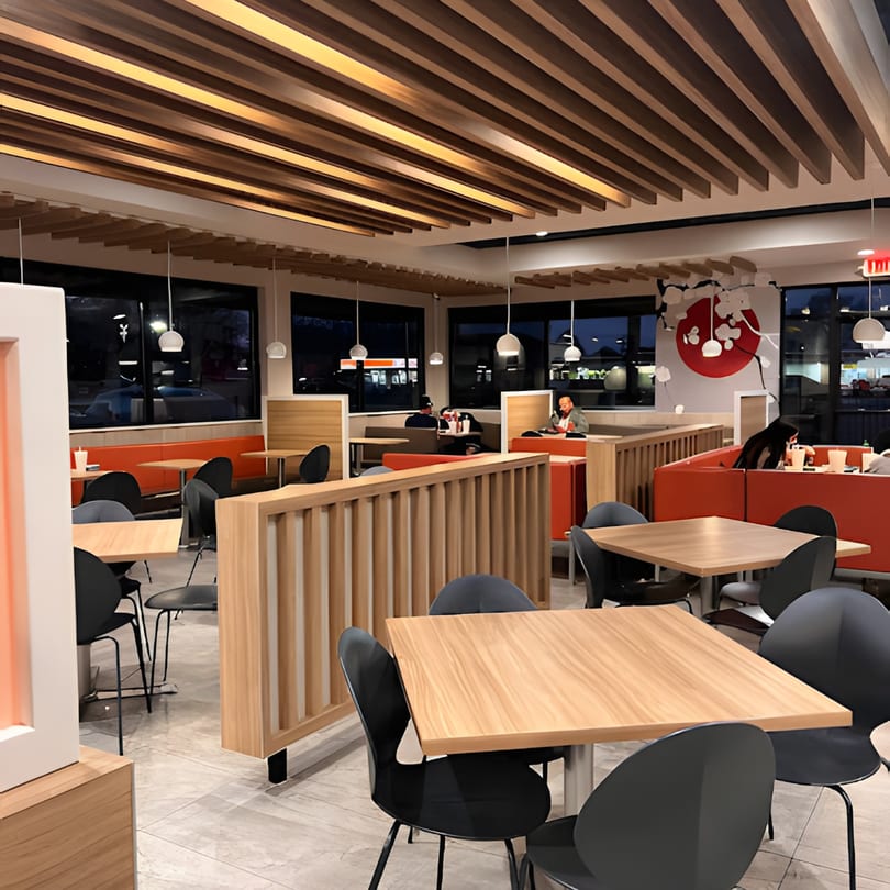 Modern Japanese restaurant interior with wooden tables, black chairs, red booths, and a cherry blossom wall mural.