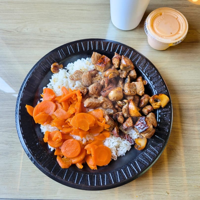 Sake Express's chicken and mushroom hibachi with rice and carrots on a black plate.